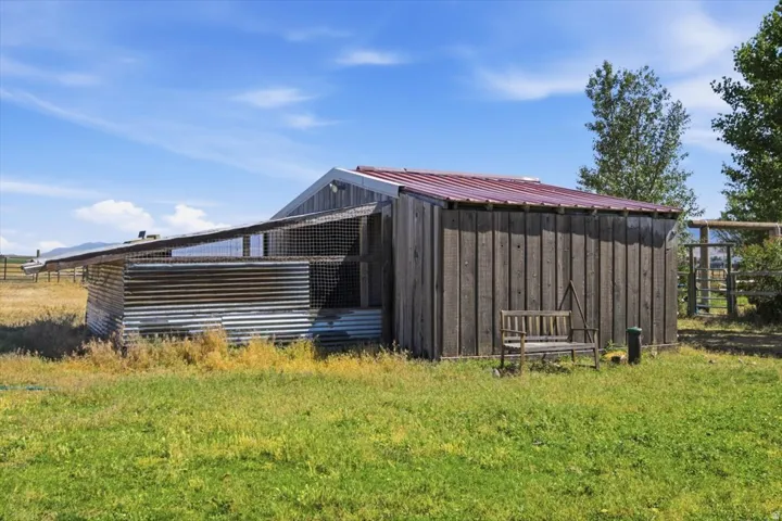 Outbuilding featuring a red metal roof, vertical wood siding, and corrugated metal panels