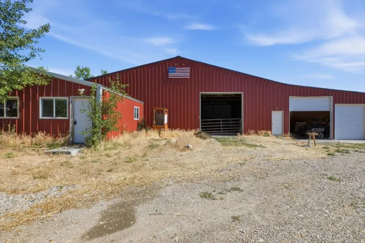 Red metal-sided barn featuring multiple large openings, including a tall, wide entry, and two additional garage doors