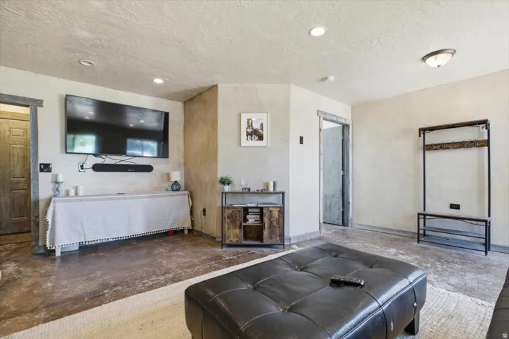 Spacious room featuring durable concrete flooring, textured walls, recessed lighting, and a semi-flush mount ceiling fixture