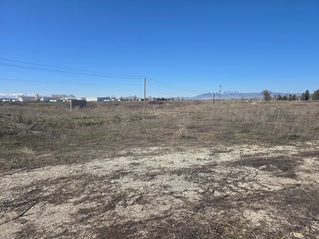 Expansive open land featuring natural vegetation and distant mountain scenery