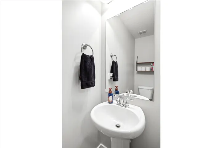 Pedestal sink with chrome faucet, large frameless mirror, and wall-mounted towel ring