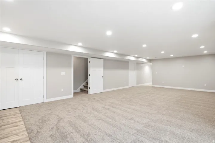 Spacious room featuring neutral carpeting, light gray walls, white trim, recessed lighting, and white paneled doors