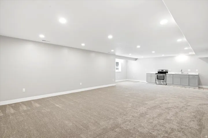 Expansive open-concept room featuring neutral-toned carpeting and recessed lighting