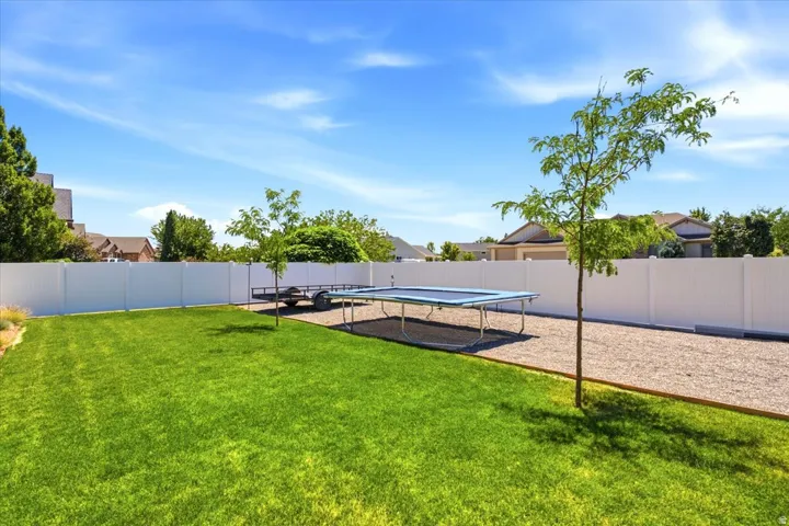Expansive backyard featuring a green lawn, gravel area, and a privacy fence