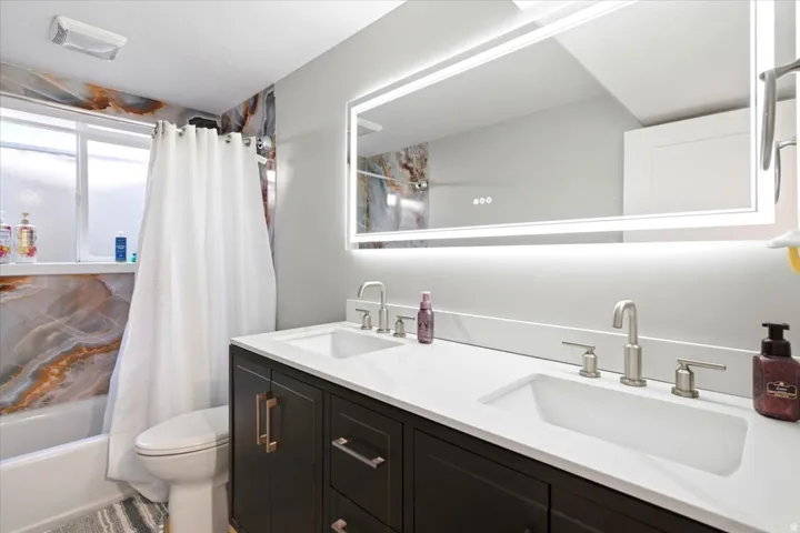 Dual vanity with integrated sinks, brushed nickel fixtures, a white countertop, and dark wood cabinetry