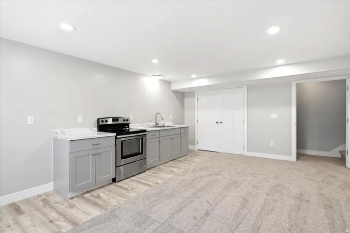 Kitchenette featuring a stainless steel range, light grey cabinetry, and stone-finish countertops