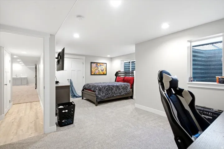 Spacious room with plush carpeting, recessed lighting, and a window with a privacy blind