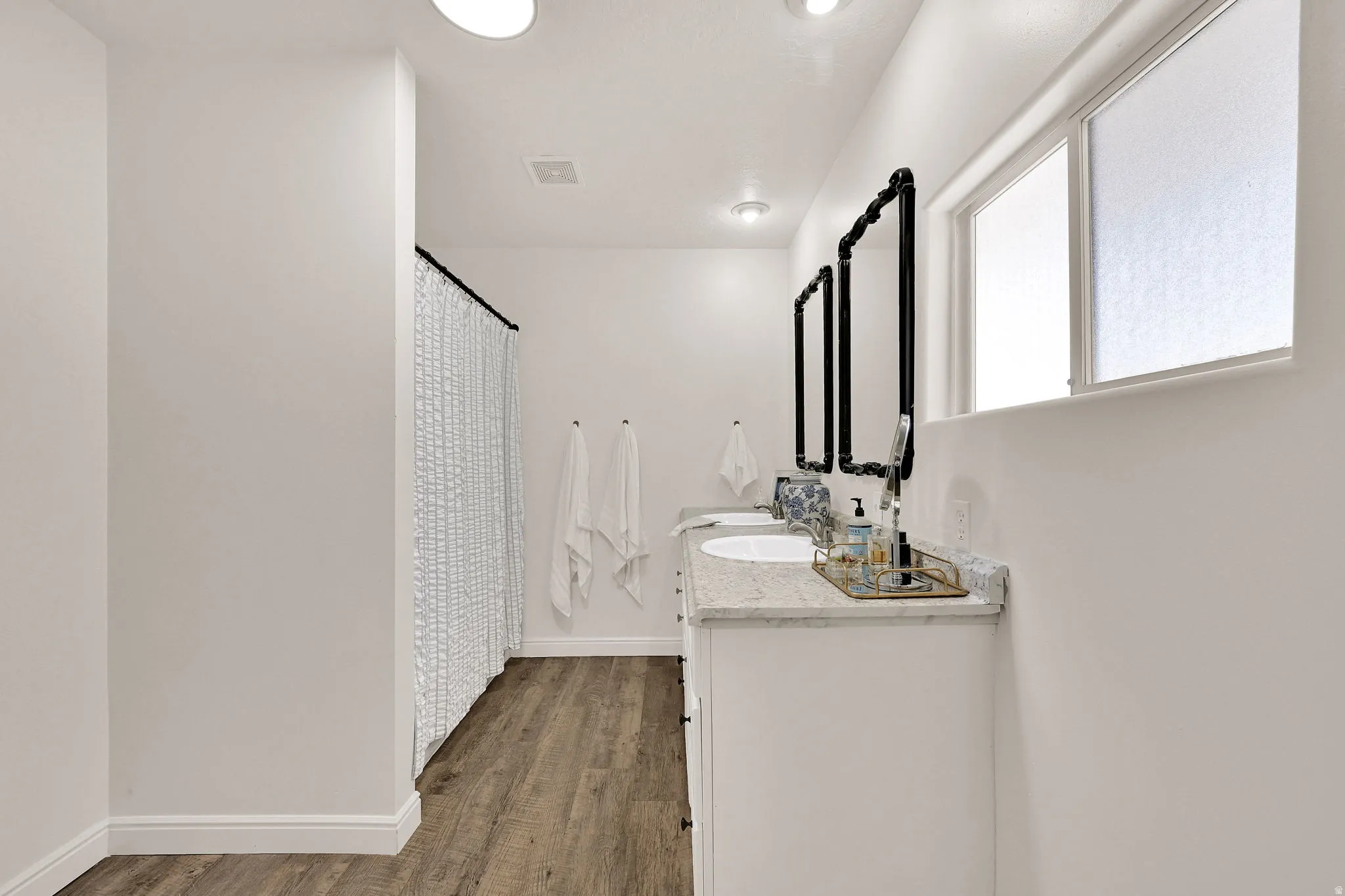 Owners ensuite featuring a double vanity with stone countertops, individual sinks, and black-framed mirrors