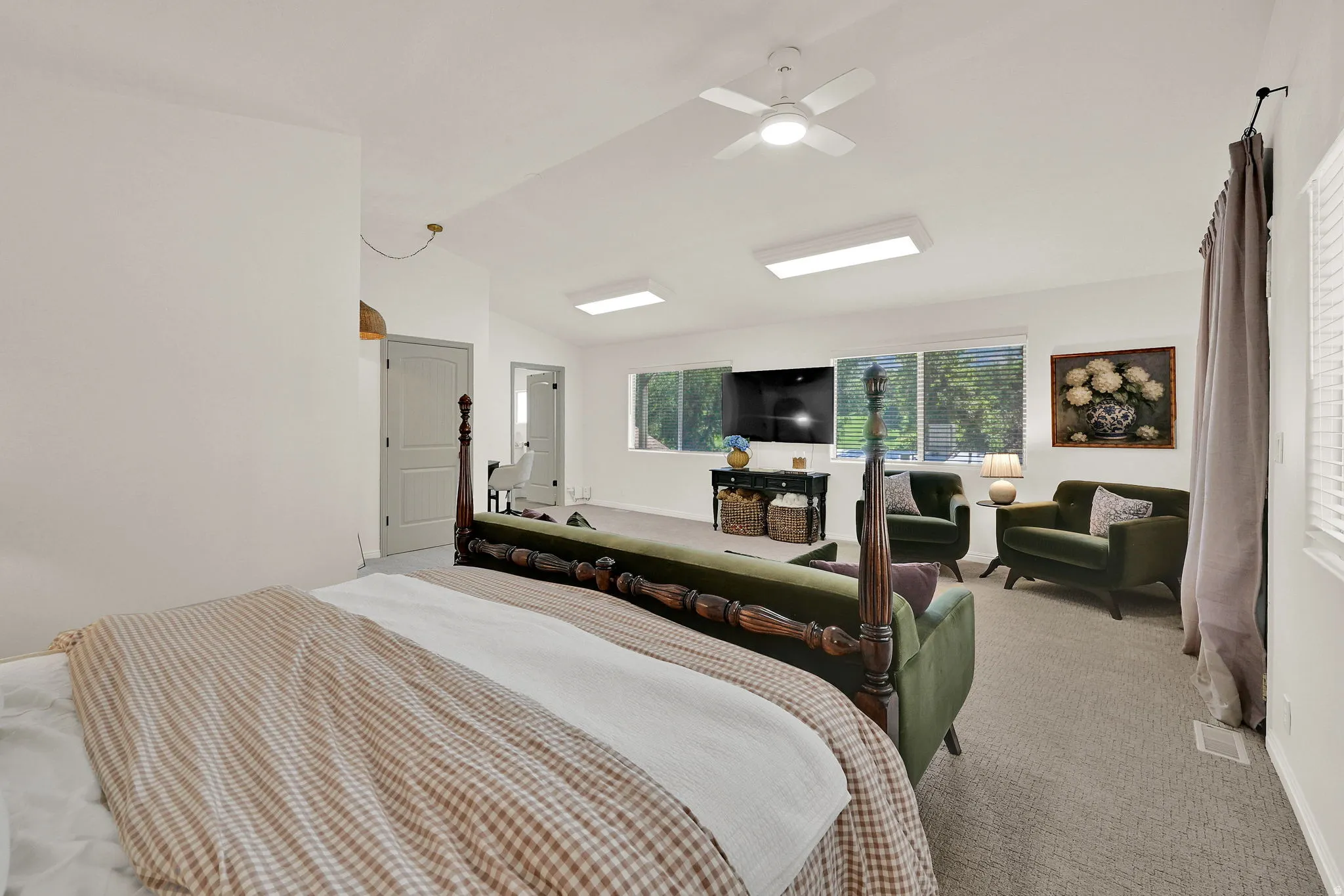 Spacious owners suite featuring vaulted ceilings, a ceiling fan with integrated lighting, recessed lighting, and multiple windows providing natural light