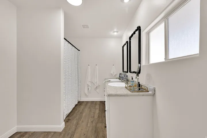Owners ensuite featuring a double vanity with stone countertops, individual sinks, and black-framed mirrors