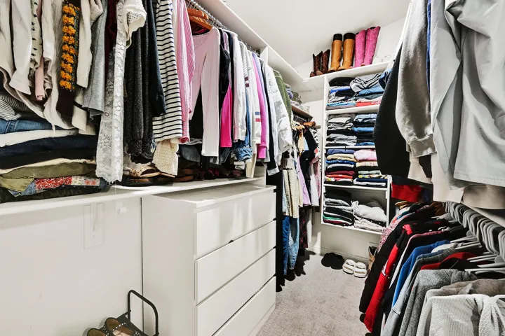 Custom owners suite built-in closet system featuring multiple hanging rods, integrated shelving units, and pull-out drawers in owners suite