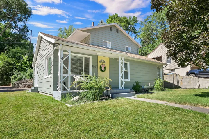 Sage green siding exterior with white trim and a covered front porch featuring decorative white supports