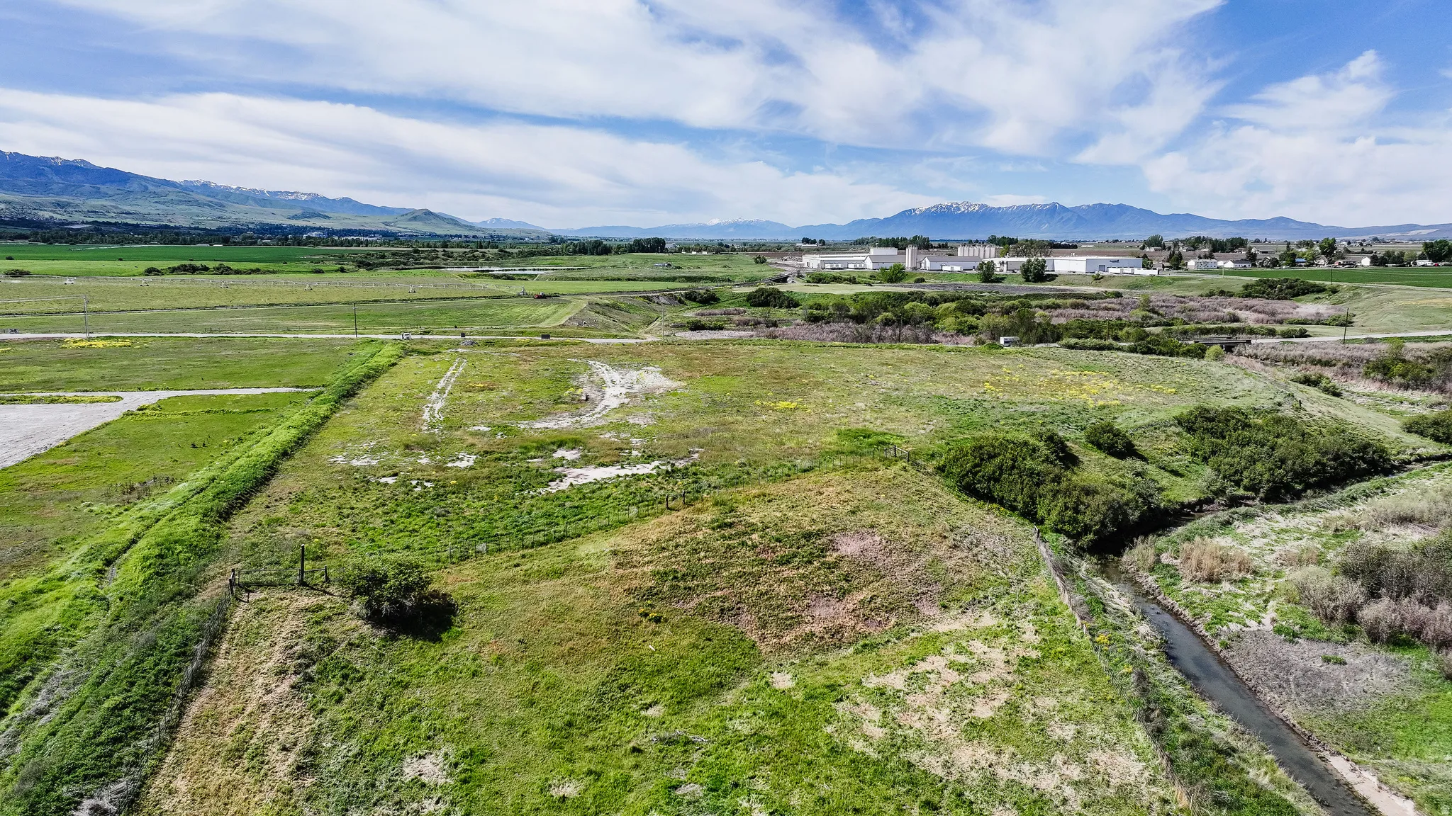 Expansive landscape featuring large parcels of undeveloped land, a natural water feature, and distant mountain ranges