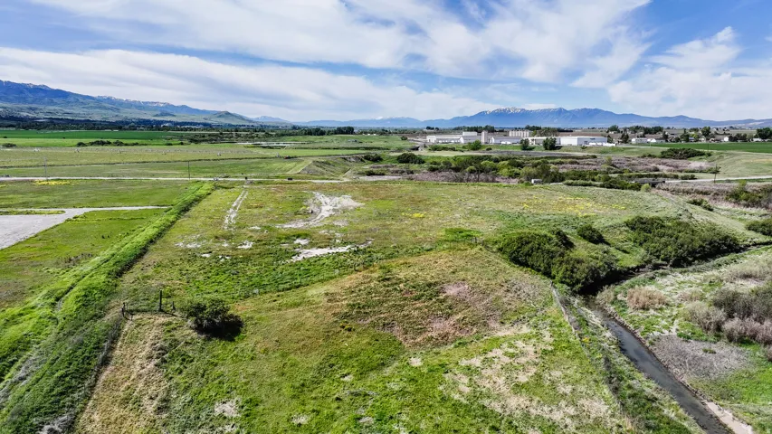 Expansive landscape featuring large parcels of undeveloped land, a natural water feature, and distant mountain ranges