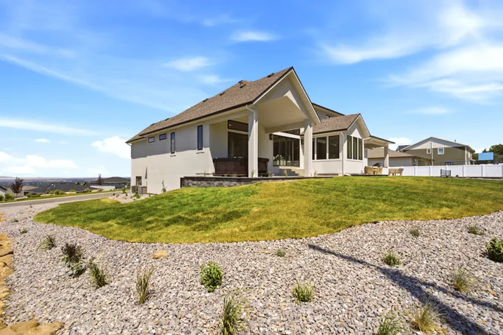 Contemporary stucco residence featuring a covered patio, extensive windows, and a sunroom