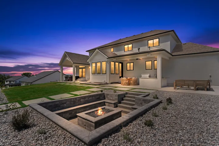 Stucco exterior home with a terraced backyard featuring a built-in fire pit, stone steps, and a spacious concrete patio