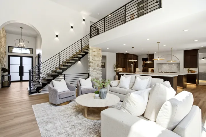 Open-concept living space featuring wood-finish flooring, a contemporary staircase with iron railings, and stone accent walls