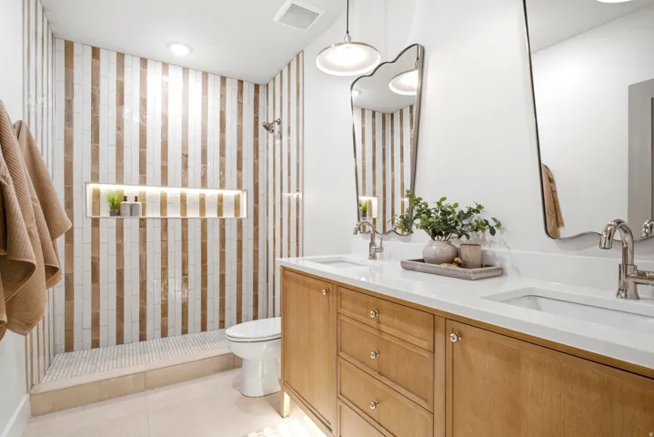 Bathroom featuring a dual vanity with light wood cabinetry, white countertops, and contemporary vessel sinks