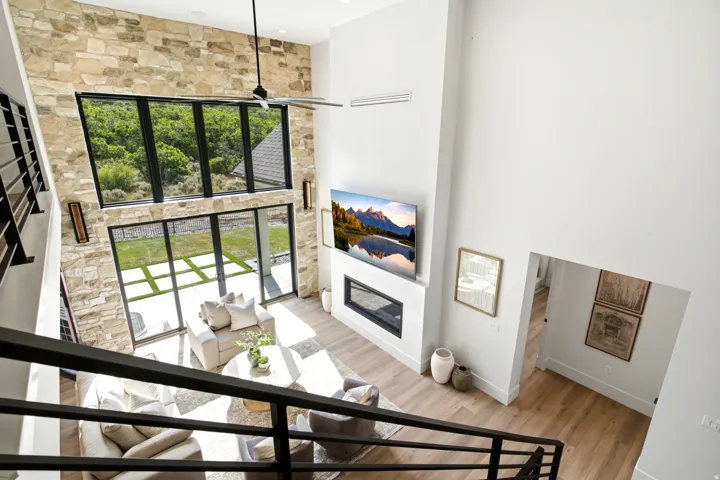 Two-story living area featuring a stone accent wall, soaring ceilings, and expansive floor-to-ceiling windows