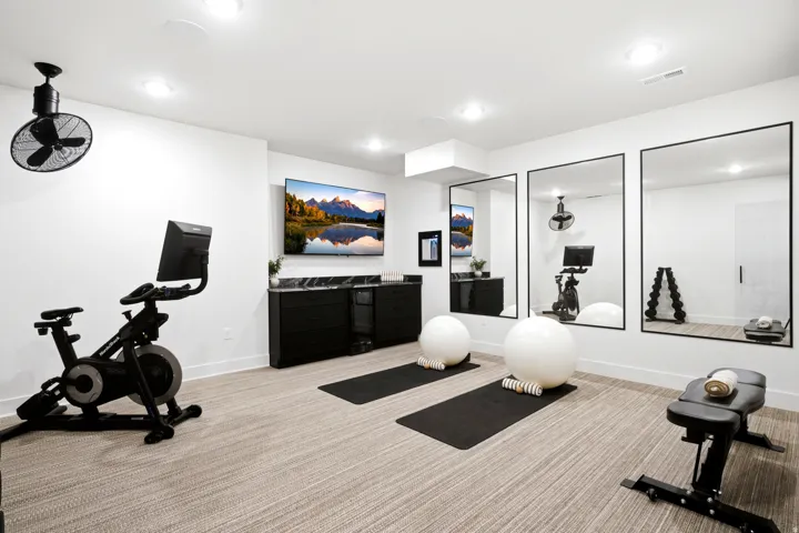 Dedicated fitness space featuring textured carpet flooring, recessed lighting, and wall-mounted mirrors