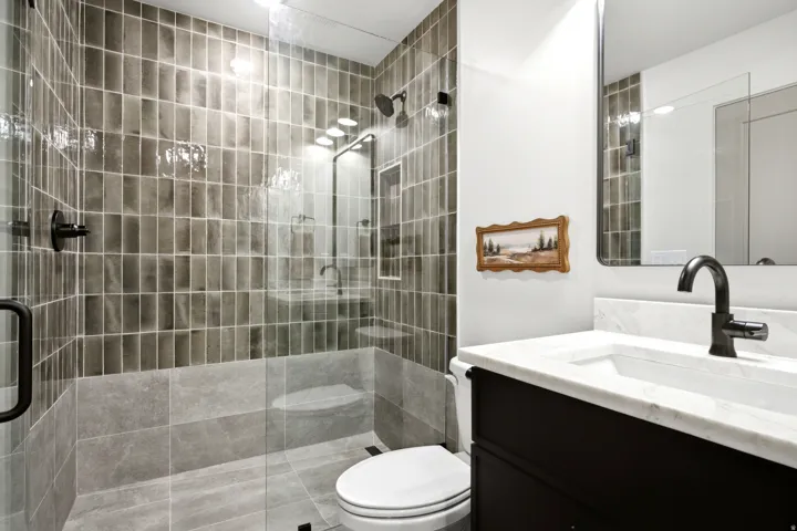 Bathroom featuring a glass-enclosed shower with vertical rectangular tiles, a built-in shower niche, and a matte black shower head