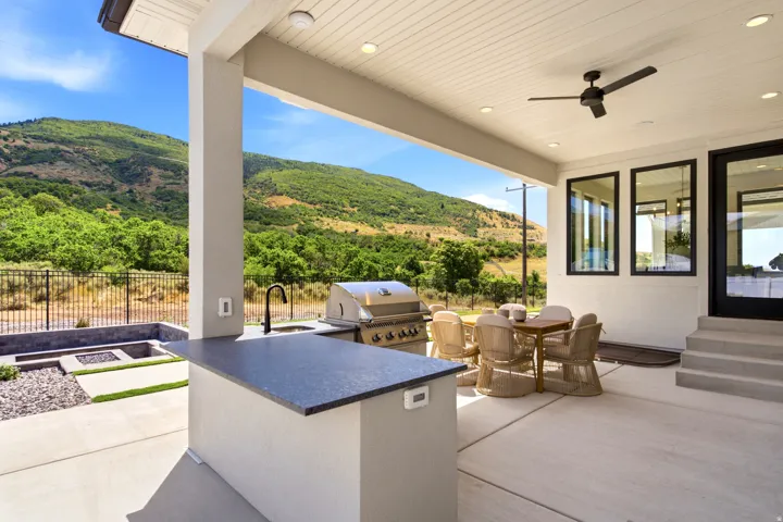 Covered patio featuring an outdoor kitchen with a built-in grill and sink, a ceiling fan, recessed lighting, and an integrated fire pit area