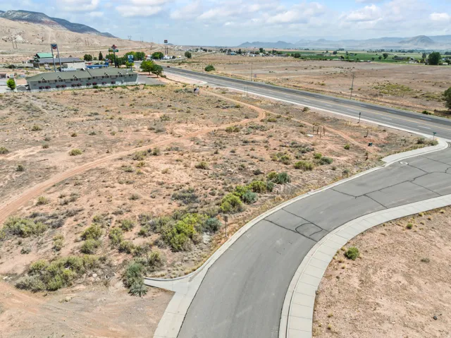 Paved cul-de-sac with concrete curbing, bordered by undeveloped desert terrain