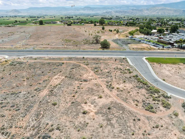 Expansive undeveloped lot featuring a paved road frontage, natural desert landscaping, and distant mountain scenery