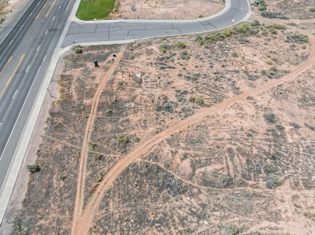Expansive undeveloped land featuring natural desert vegetation, a paved roadway, and a paved cul-de-sac