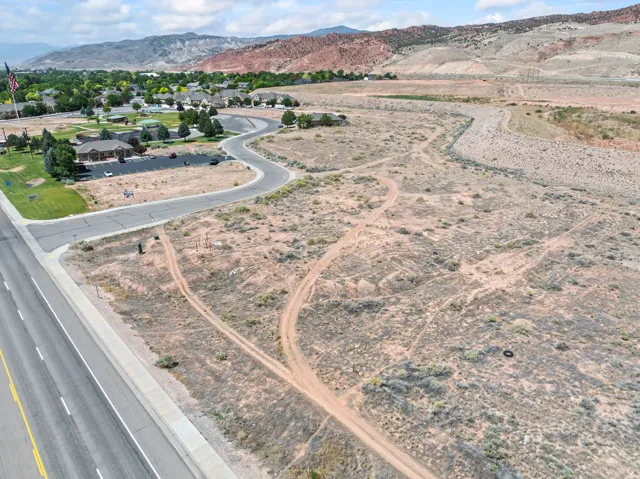 Expansive undeveloped land featuring a paved road frontage, established curb and gutter, and access to an existing residential area