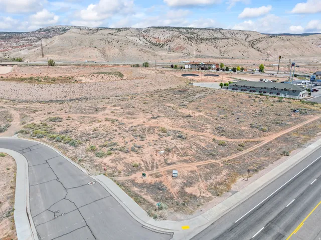 Expansive desert lot featuring a paved road frontage, curved sidewalk, and a backdrop of mountainous terrain