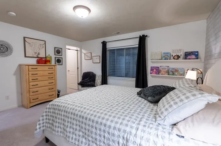 Bedroom featuring neutral wall paint, light-toned carpeting, and a window with blinds