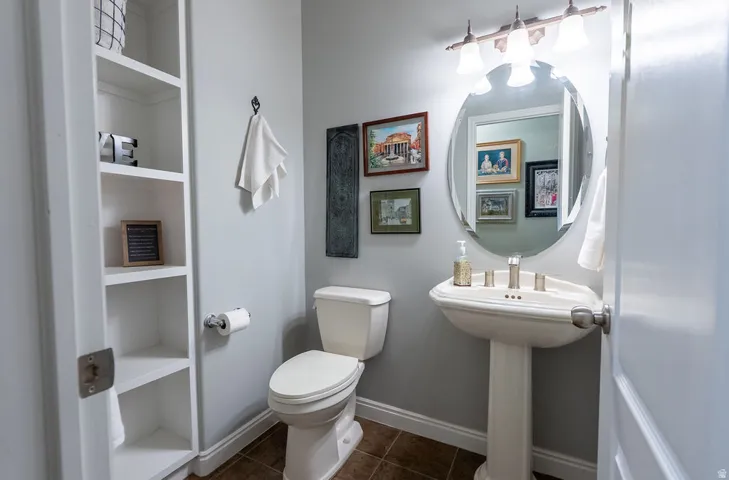 Pedestal sink with brushed nickel faucet, wall-mounted mirror, and vanity lighting