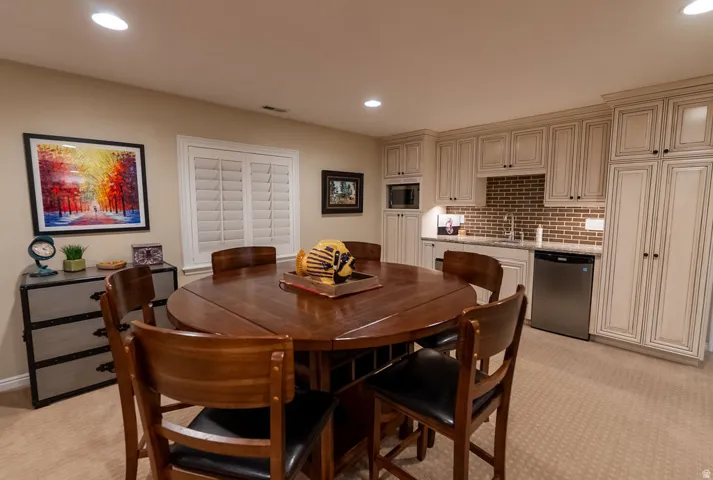Built-in kitchenette featuring full-height cabinetry, brick-style backsplash, stainless steel sink, and integrated microwave