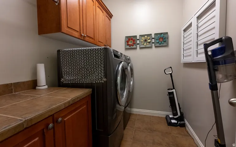 Dedicated laundry area featuring cabinetry, tile flooring, and a tile countertop