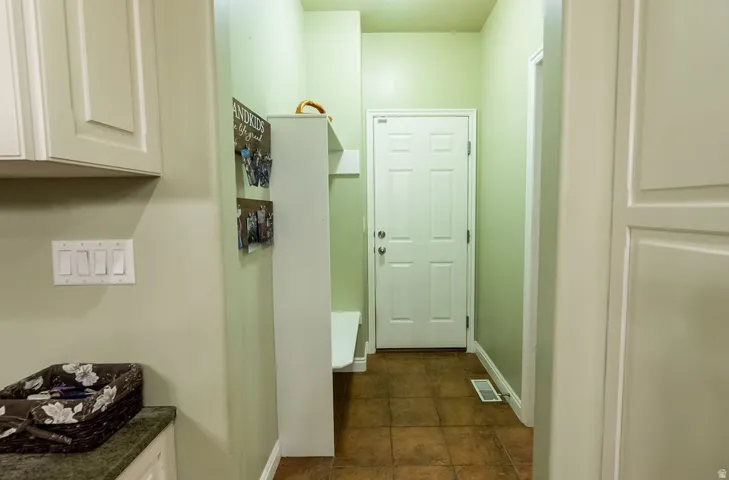 Entryway featuring a six-panel door, terracotta-toned tile flooring, and a built-in storage bench with shelving