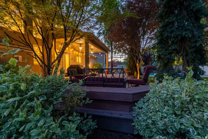 Expansive outdoor area featuring a multi-level wood-finish deck with integrated steps, a covered patio, and mature landscaping