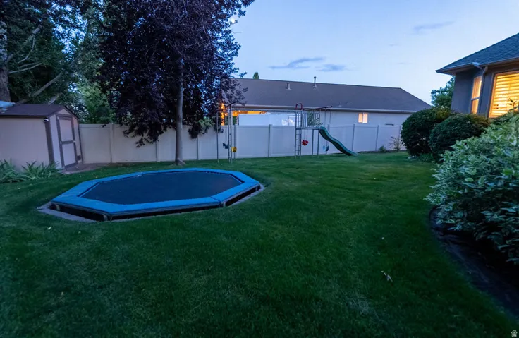 Expansive green lawn with mature landscaping and a perimeter privacy fence