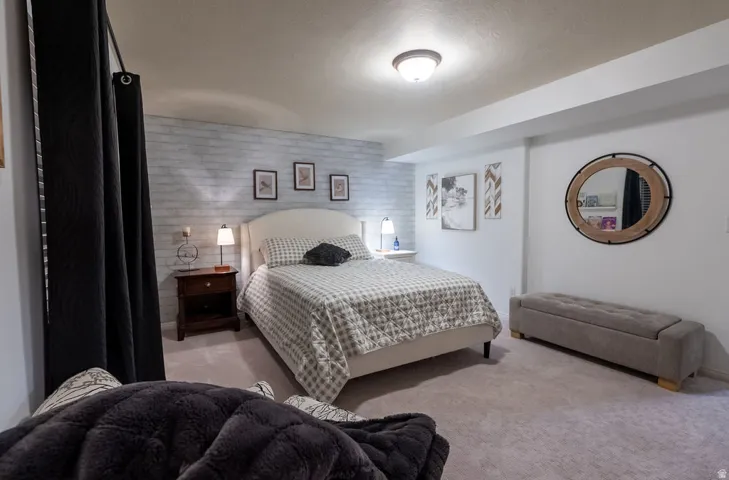 Carpeted interior space featuring a textured accent wall and a white wall finish