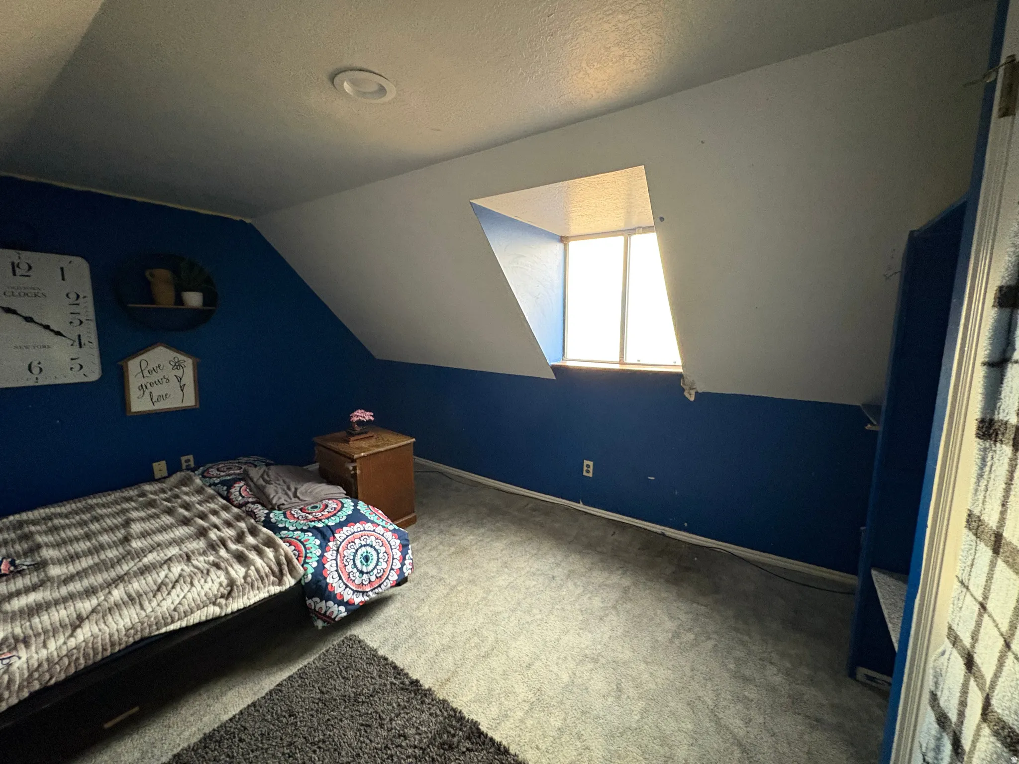 Sloped ceiling bedroom featuring a dormer window, recessed lighting, and blue wall paneling