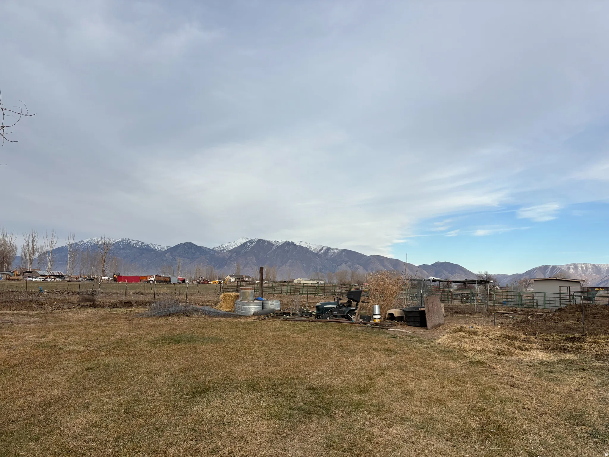 Expansive property with a grass field, fenced areas, and distant snow-capped mountains