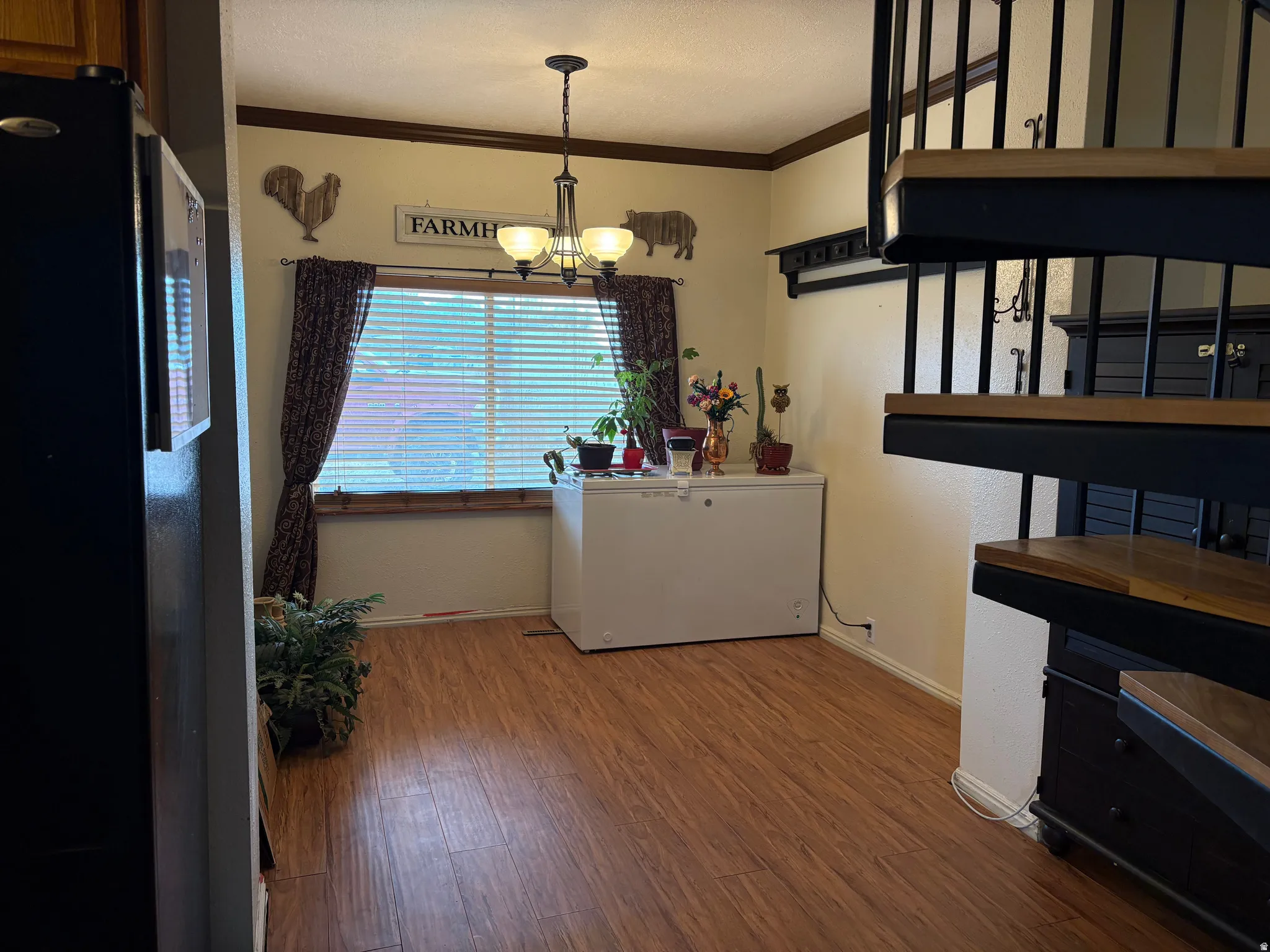 Dining area featuring wood-finish flooring, a window with horizontal blinds, and a chandelier light fixture