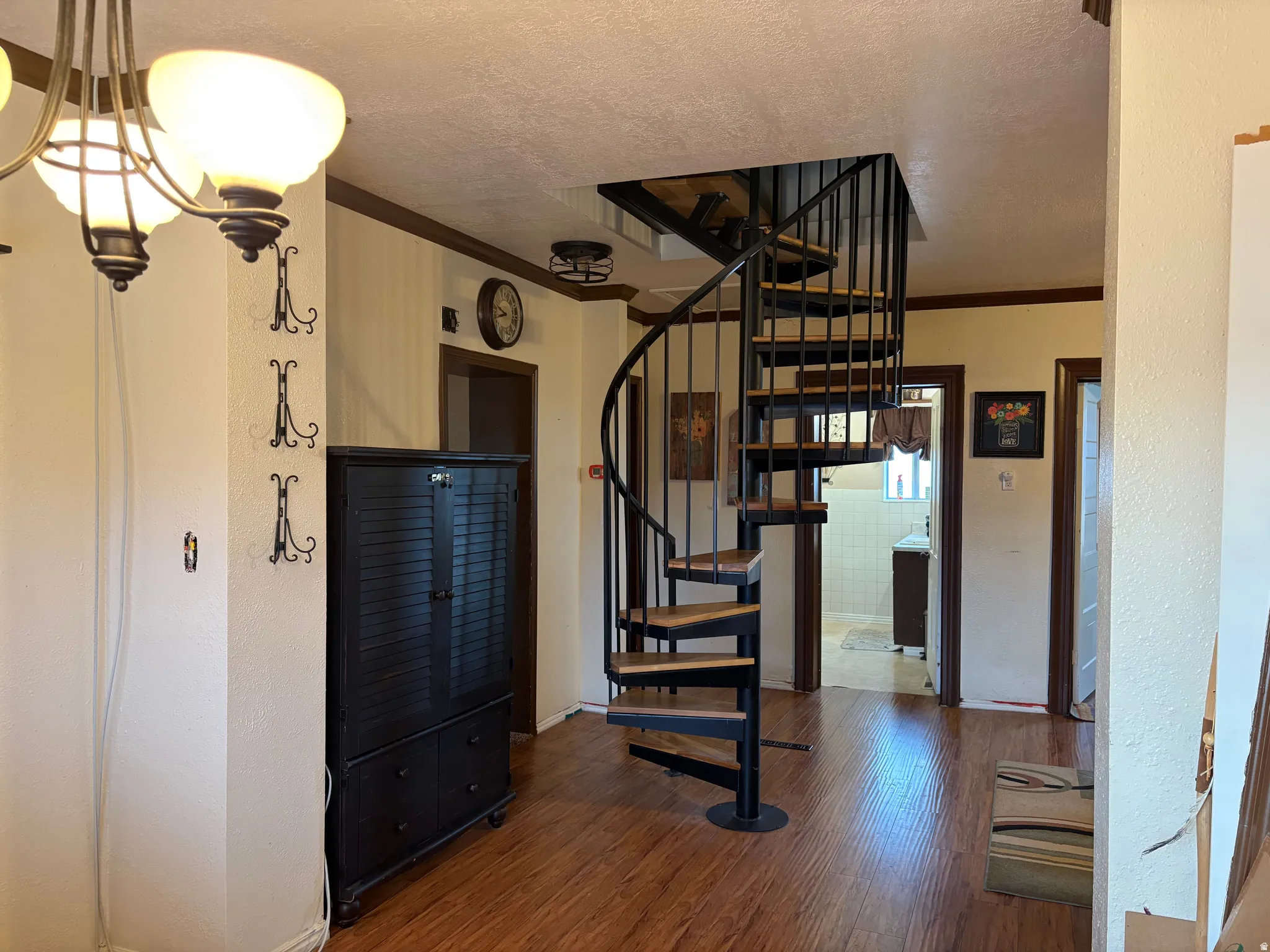 Wood-finish flooring throughout, featuring a spiral staircase with black metal railing and wood treads