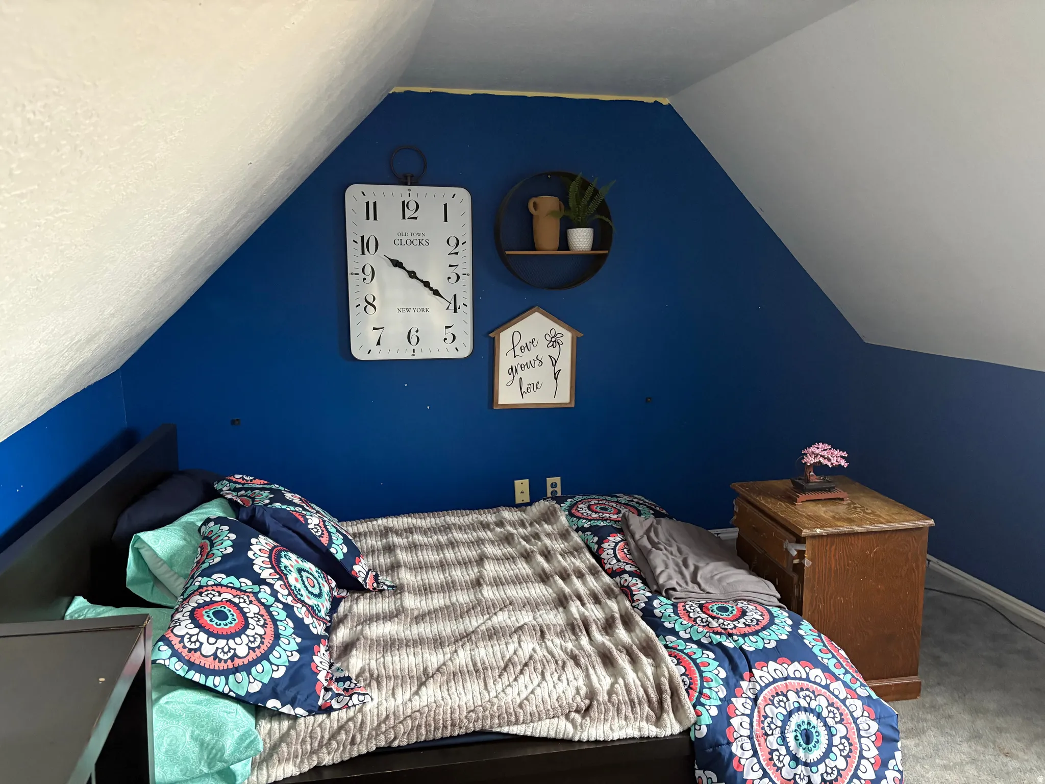 Bedroom featuring an angled ceiling, blue accent wall, and gray carpet flooring