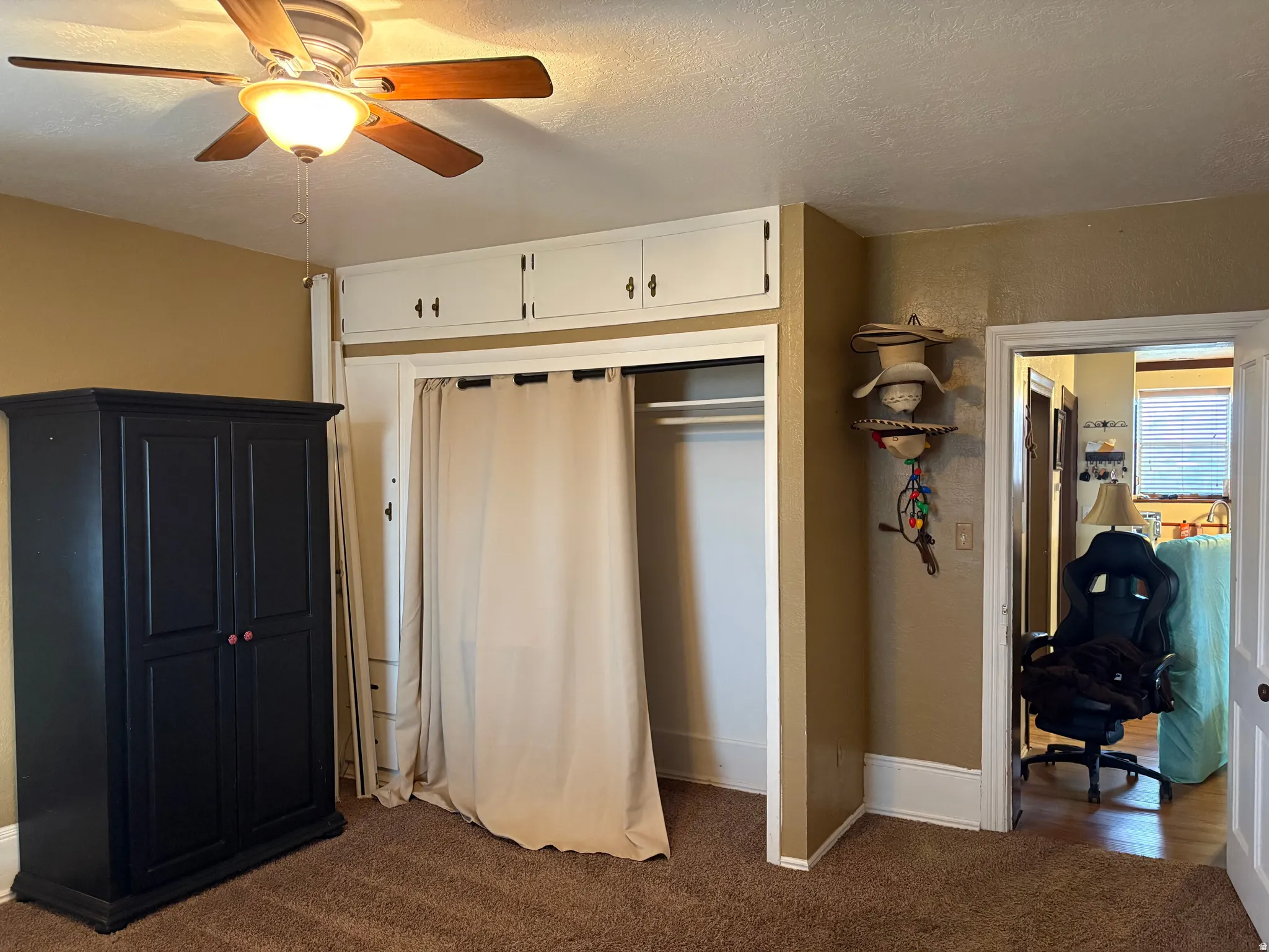 Recessed closet with curtain entry, overhead storage cabinetry, and a ceiling fan with integrated lighting