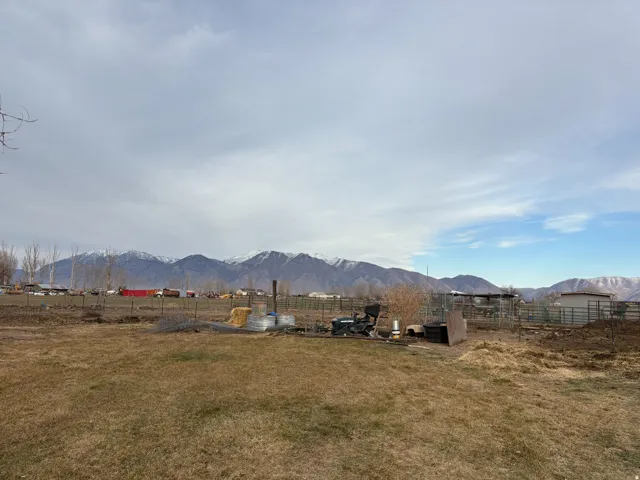 Expansive property with a grass field, fenced areas, and distant snow-capped mountains