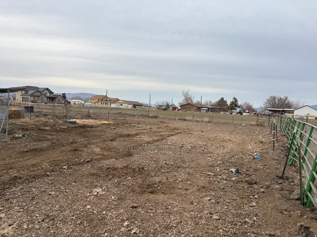 Expansive open lot featuring a perimeter fence and varied ground cover