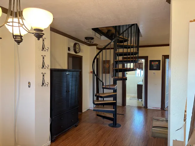 Wood-finish flooring throughout, featuring a spiral staircase with black metal railing and wood treads