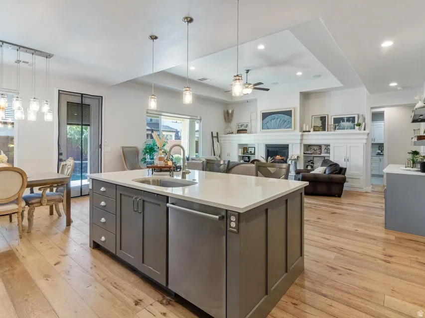 Kitchen island with a light-toned countertop, integrated sink, and stainless steel dishwasher