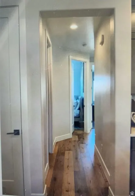 Hallway featuring wide plank wood-finish flooring, recessed lighting, and white baseboards